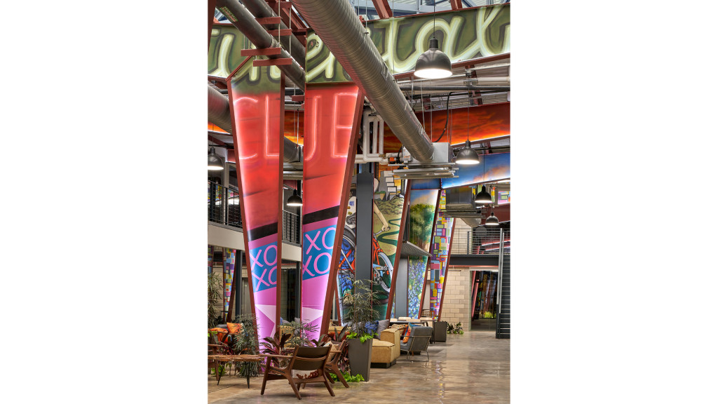 A room with a large bookcase and chairs.
